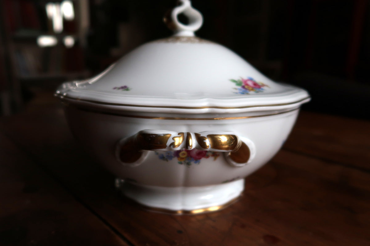Side profile showing gold-accented scrolled handle, floral bouquet and footed base
