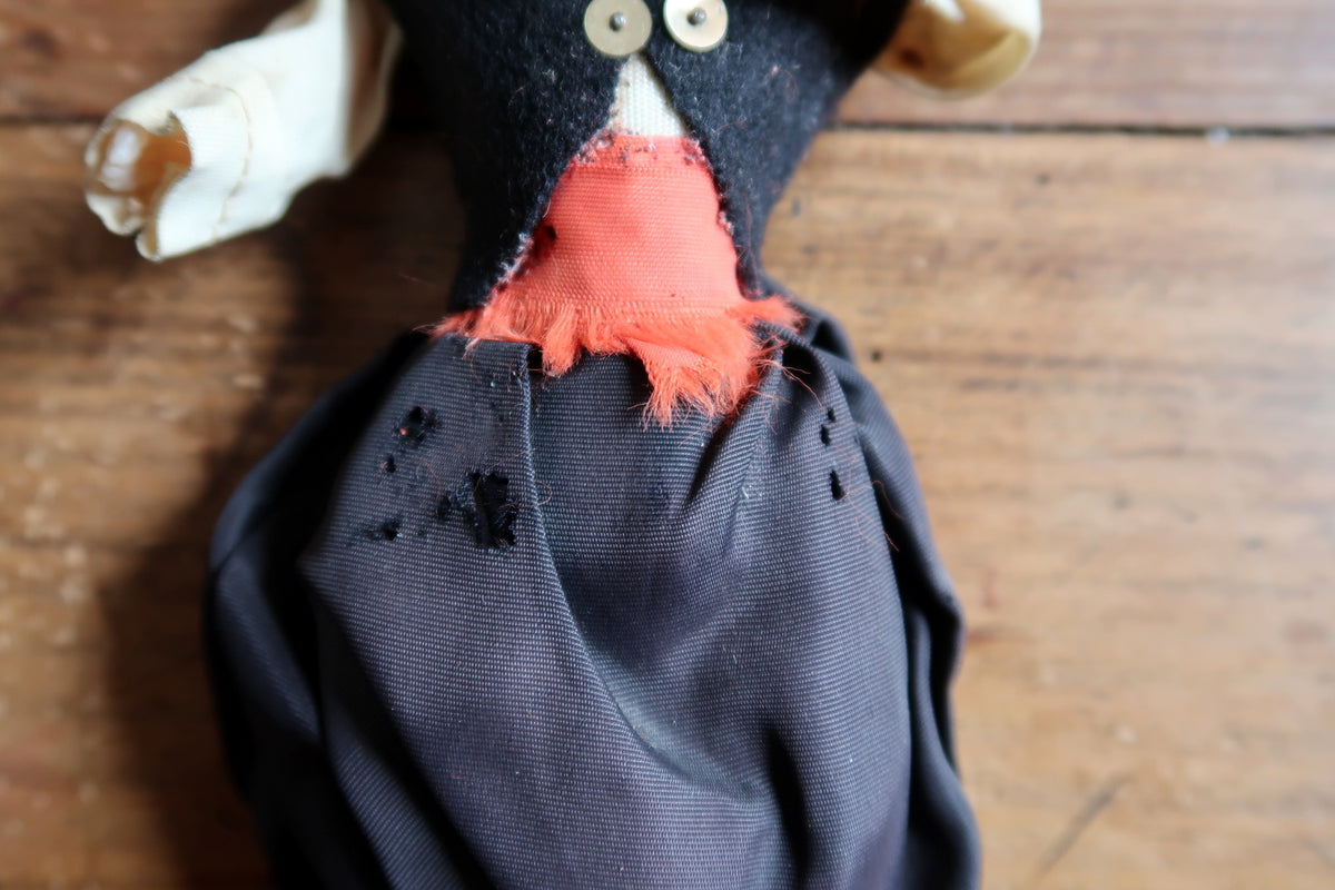 Holes in black breeches beneath the frayed red sash