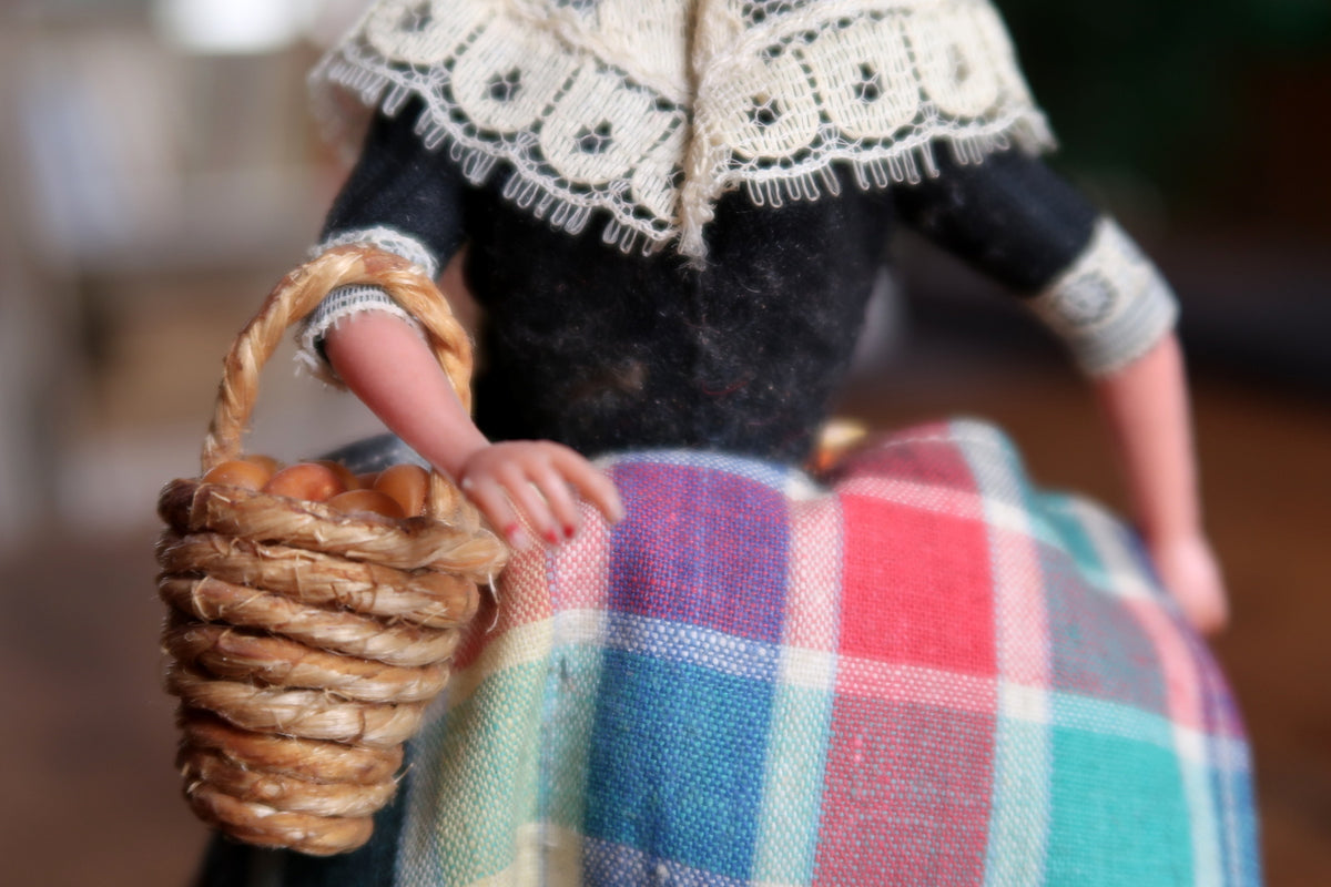 Small woven basket hanging from the doll's right arm