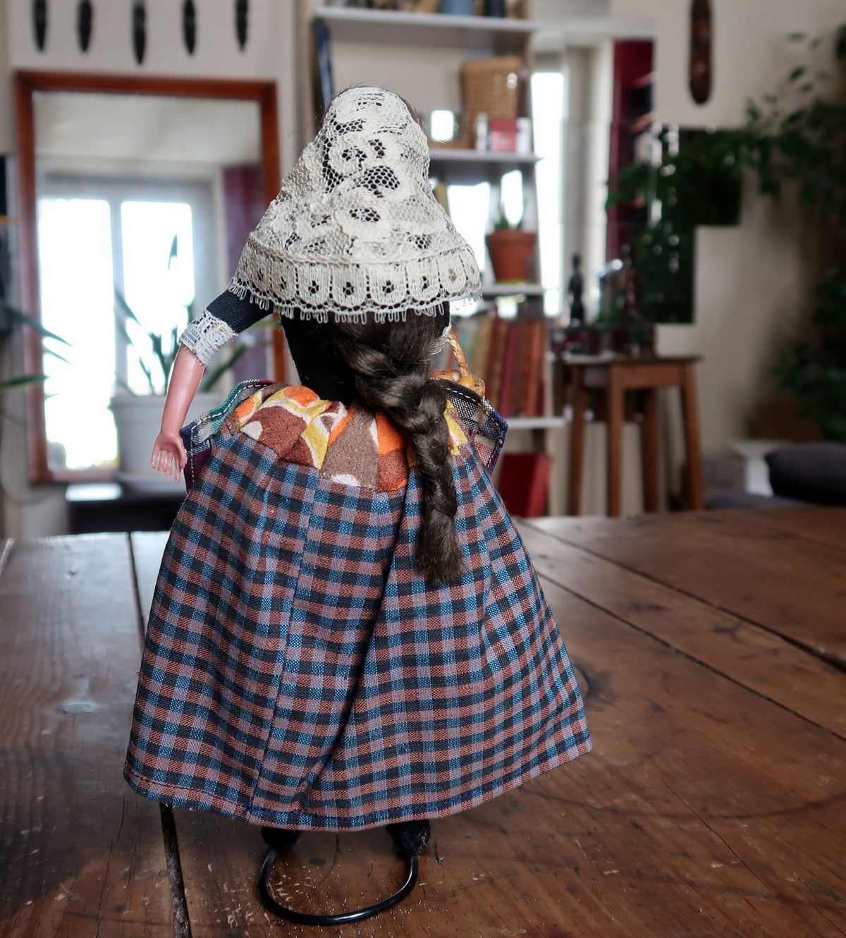 Rear view showing long brown braid and checked skirt