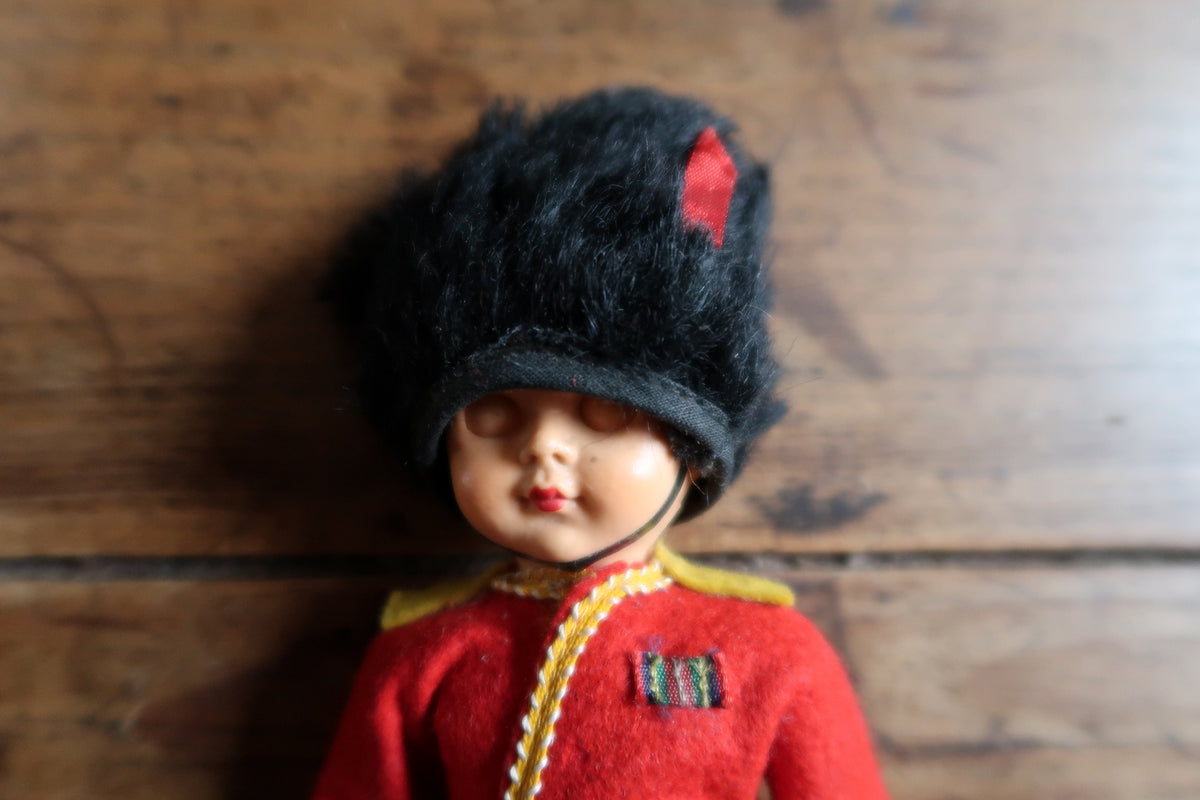 Black bearskin-style hat with red fabric accent and chin strap