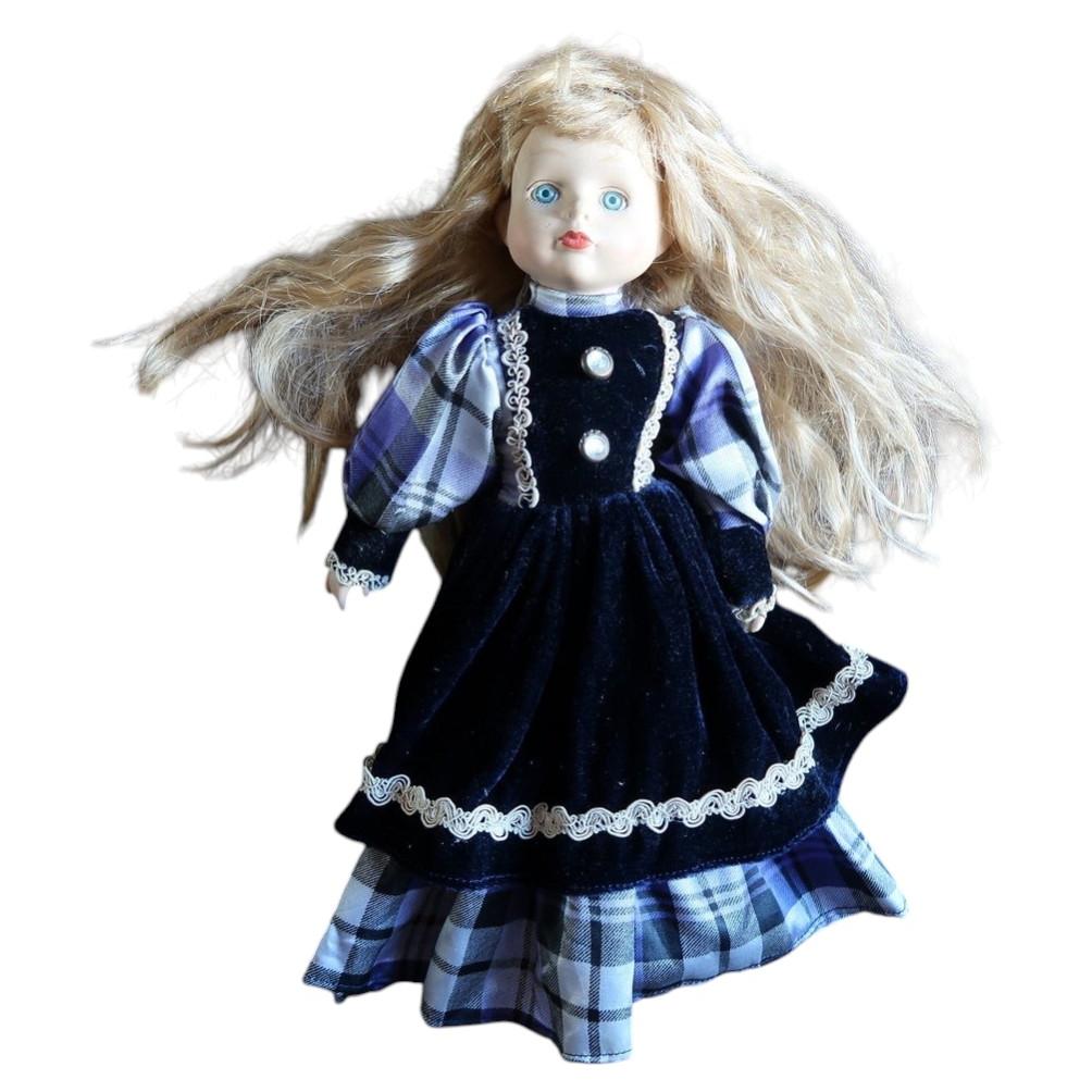 Vintage blonde porcelain doll wearing a navy velvet-style dress with plaid sleeves and underskirt.