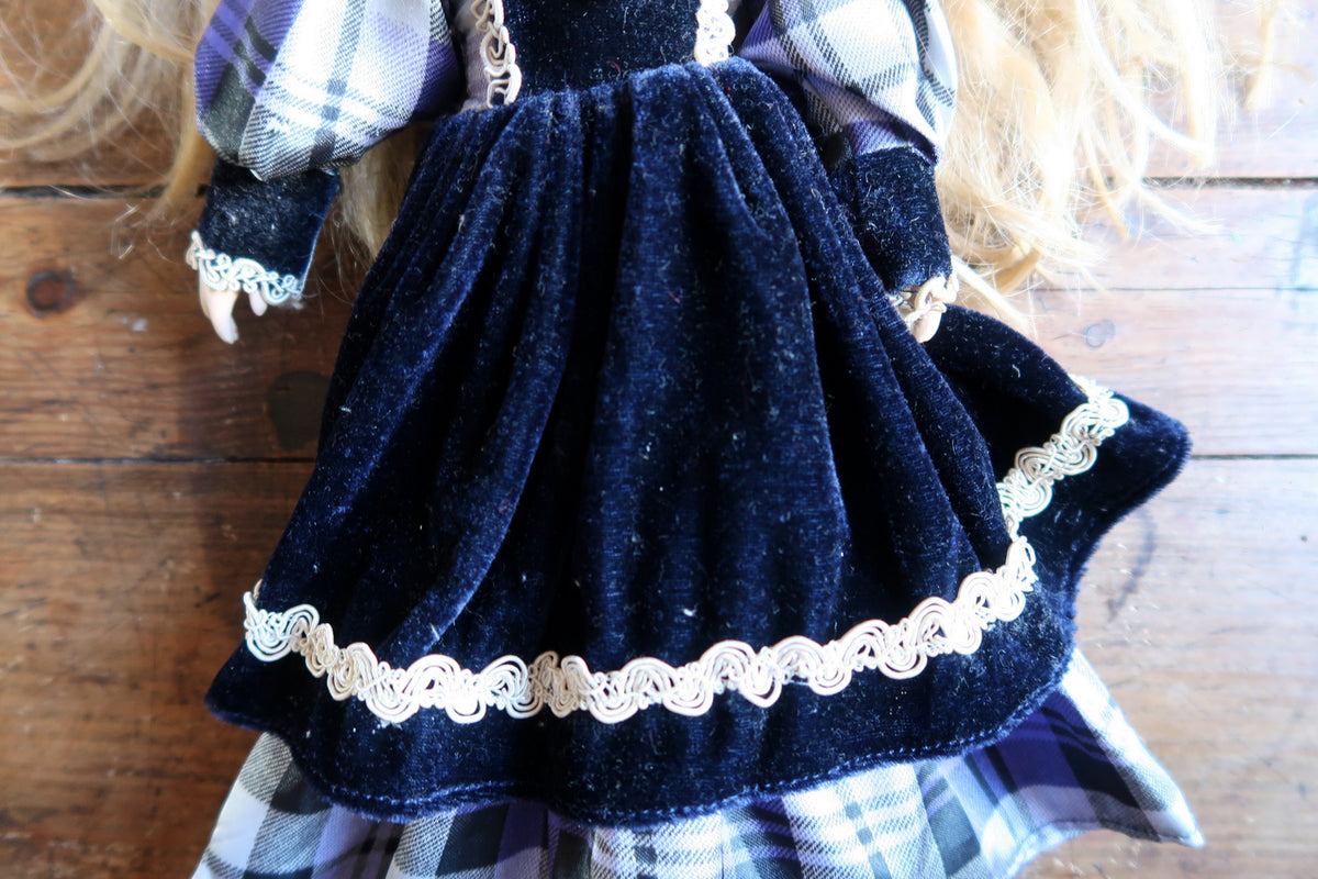 Porcelain hand extending from a navy cuff trimmed with pale decorative braid.