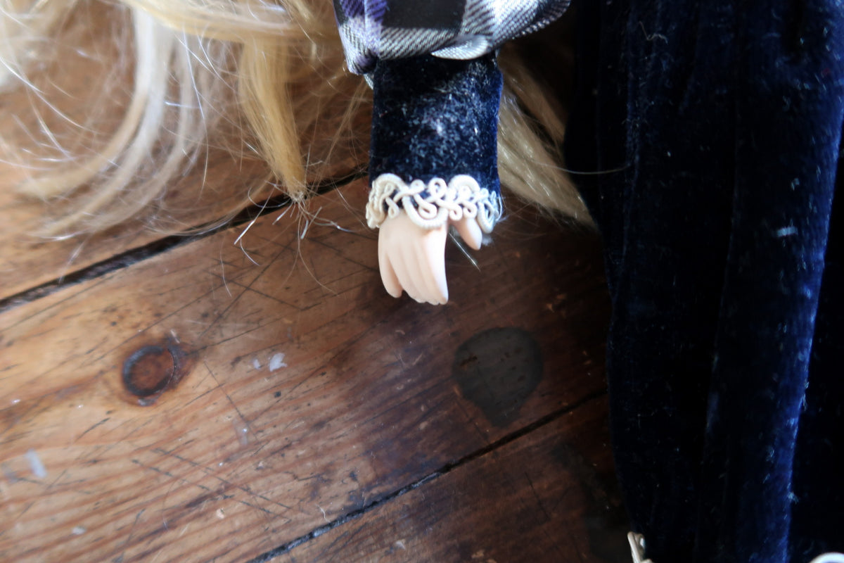 Close-up of the porcelain hand and white braid at the sleeve cuff.