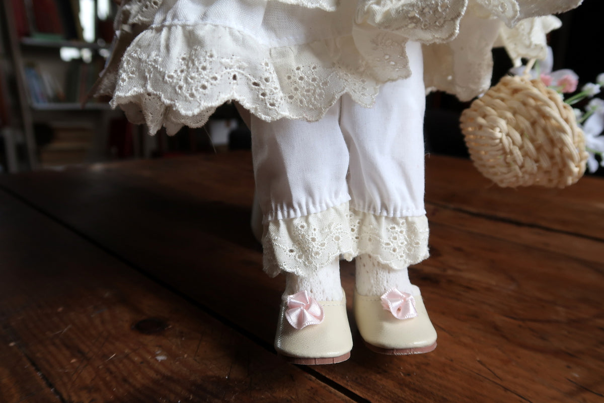 Woven basket containing artificial white and pink flowers beside the embroidered skirt.