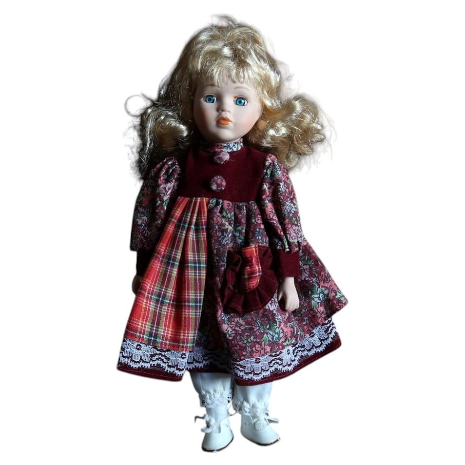 Vintage blonde porcelain doll in burgundy, floral and red tartan dress with white ankle boots.