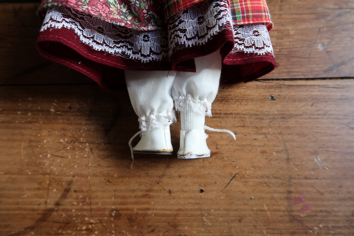 Porcelain hand beside a burgundy cuff, floral skirt and front fabric pouch.