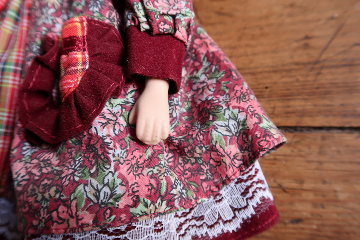 Full back view showing blonde curls, tartan skirt panel and lace-trimmed hem.