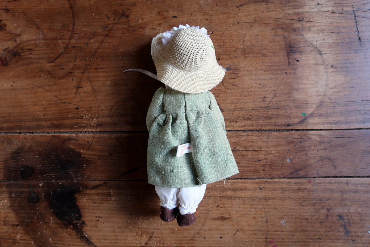 Pale woven doll hat decorated with white artificial flowers and pale yellow-green centres.