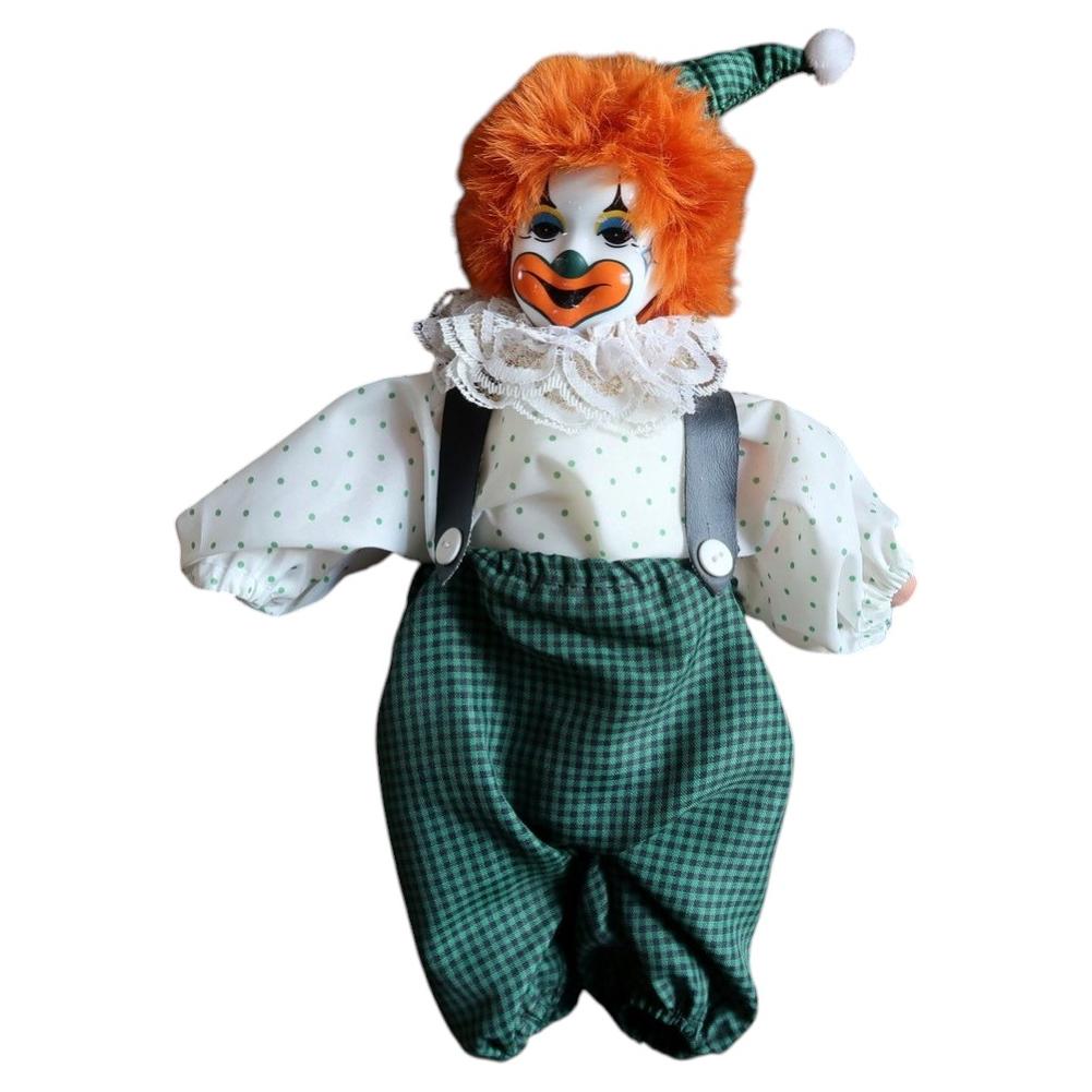 Vintage ceramic-head clown doll with orange hair, green gingham trousers and a pointed pompom hat.