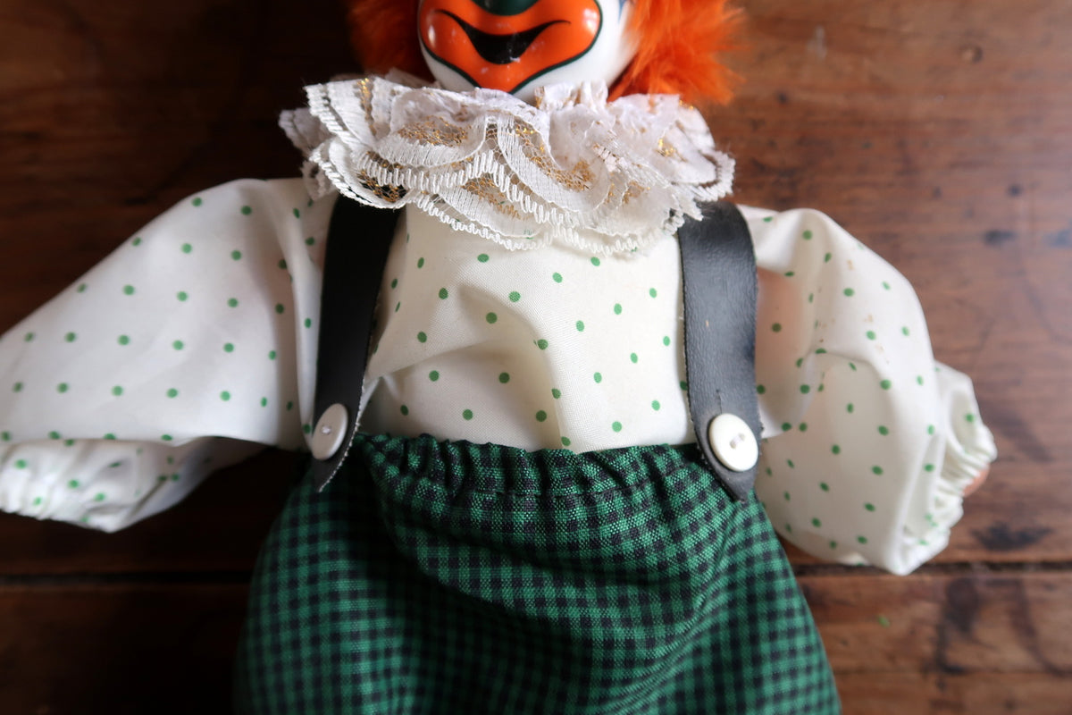Full front view of the clown doll with orange hair and matching gingham hat and trousers.