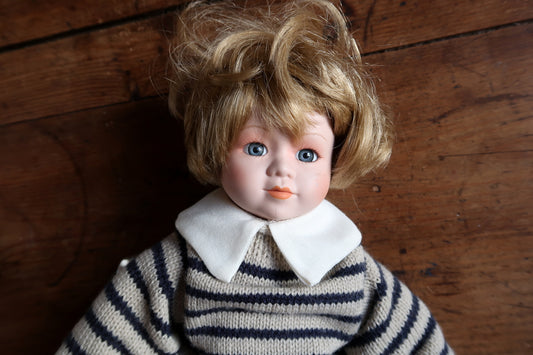 Rear view of tousled blonde hair above the white collar and striped sweater.