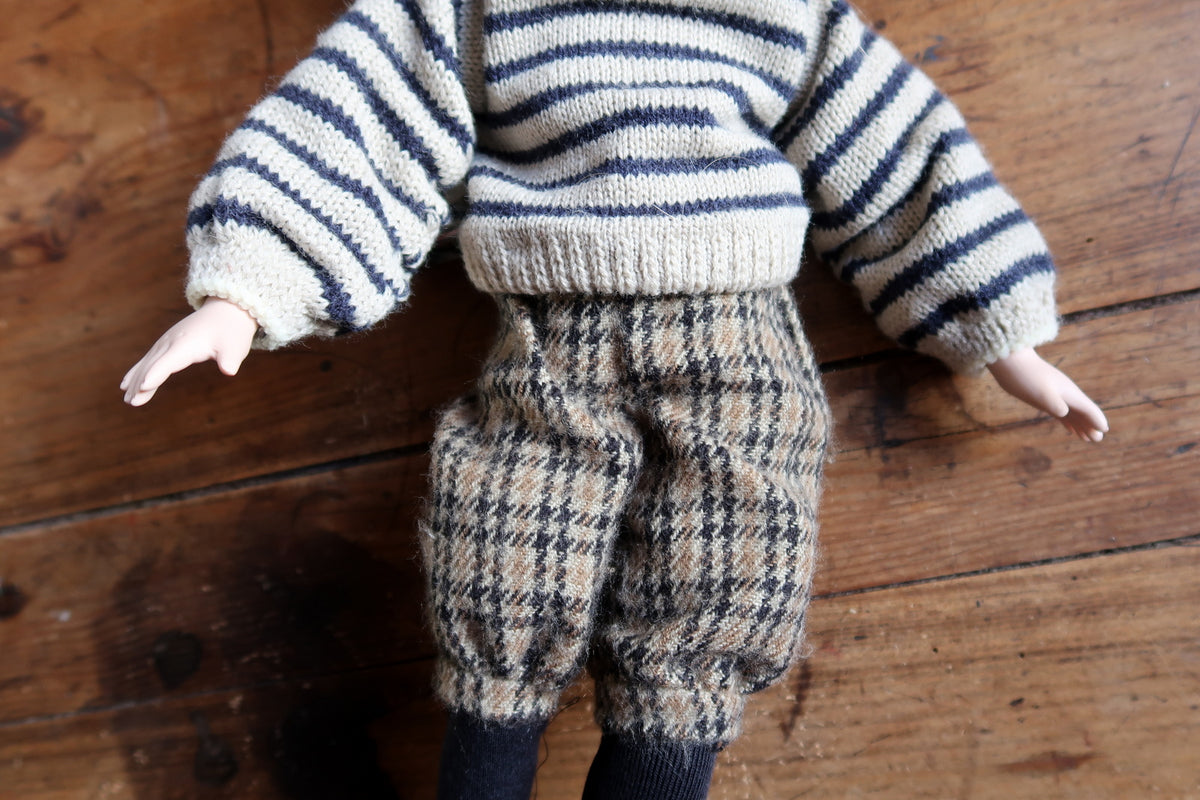 Full rear view of the boy doll in striped knitwear, checked breeches and dark socks.