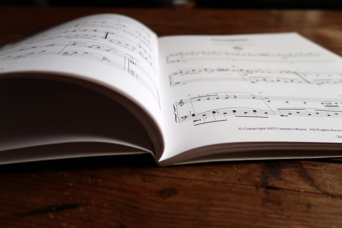 Low-angle open songbook showing curved score pages and the softcover binding.