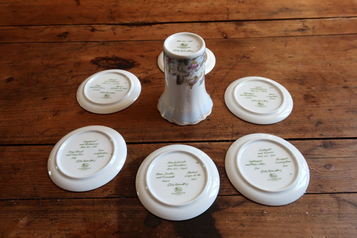 Reverse view of the six porcelain plates and vase showing their underside markings.