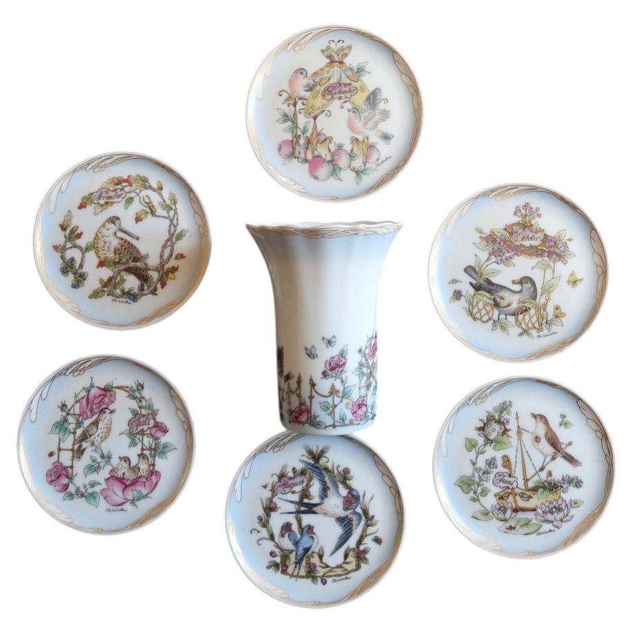 Hutschenreuther Ole Winther porcelain group of six miniature bird plates and a flared floral vase with gold decoration.