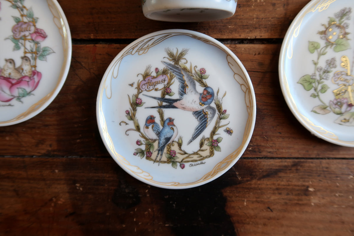 August miniature porcelain plate with swallows, floral stems, script month label and gold rim decoration.
