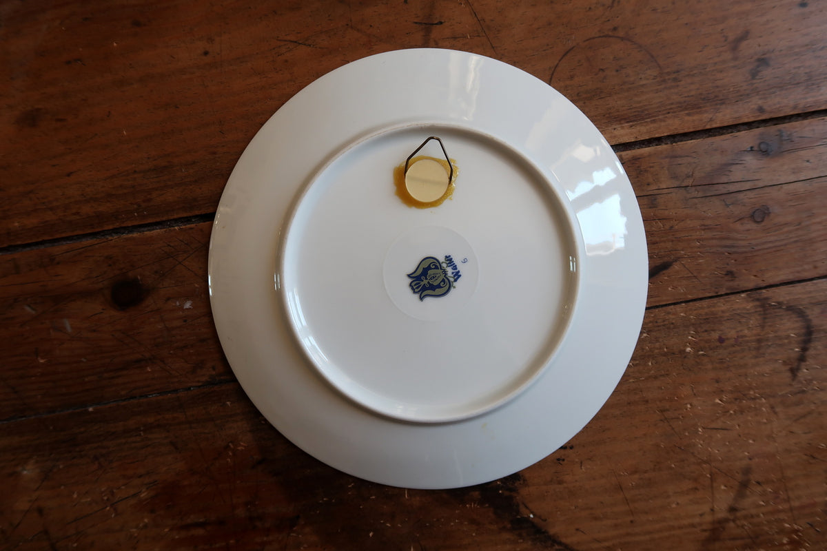 White reverse of the decorative plate with tulip maker mark and attached wire hanging loop.