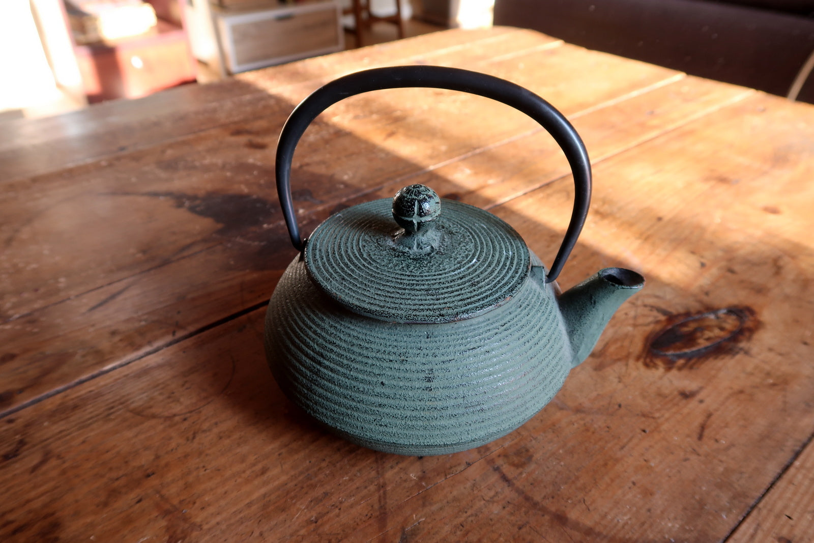 Cast iron teapot close-up, green finish with smooth minimalist surface