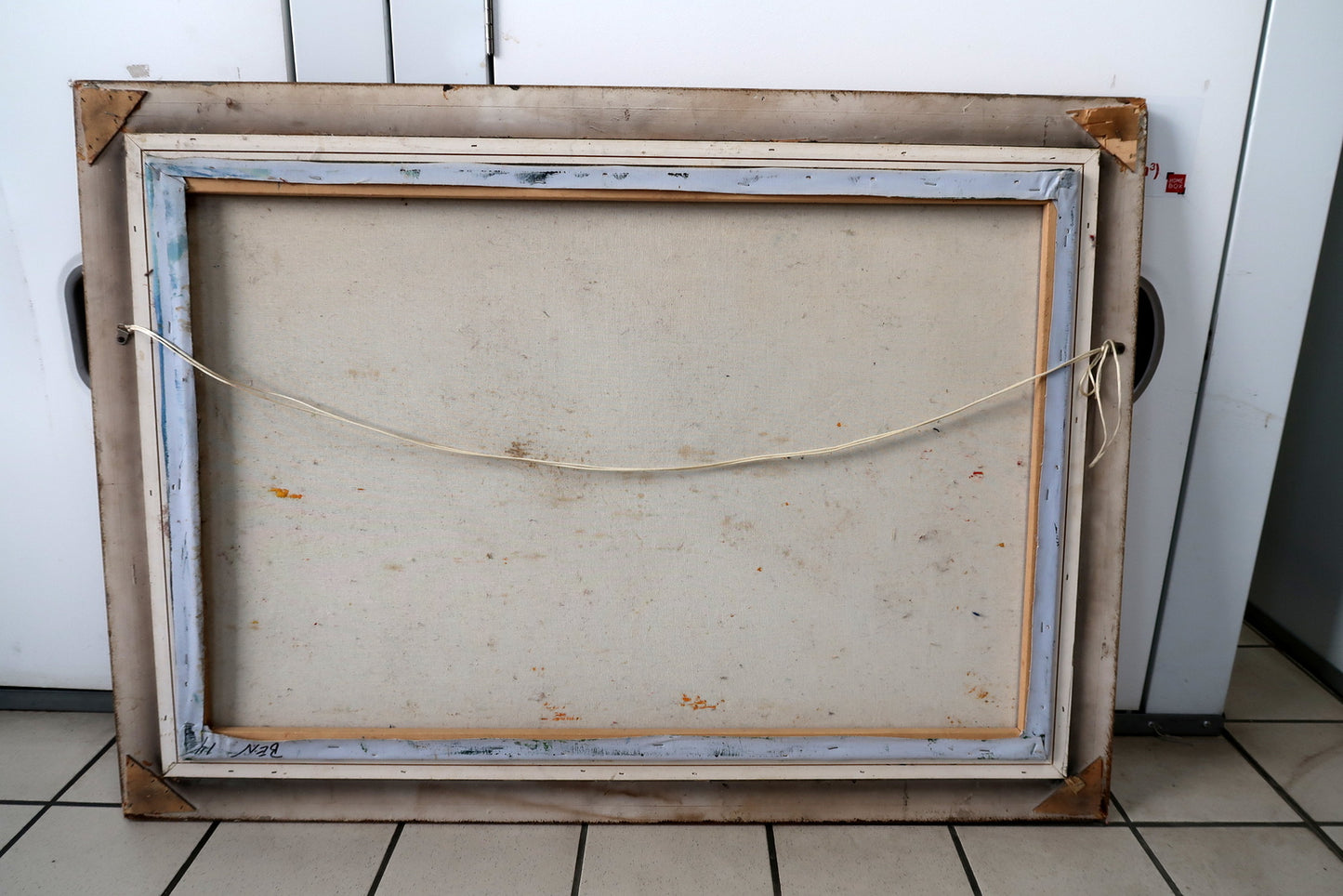Close-up of the ornate gilded frame corner showing visible cracks and wear consistent with age, surrounding a vintage oil painting of a mother and child.

