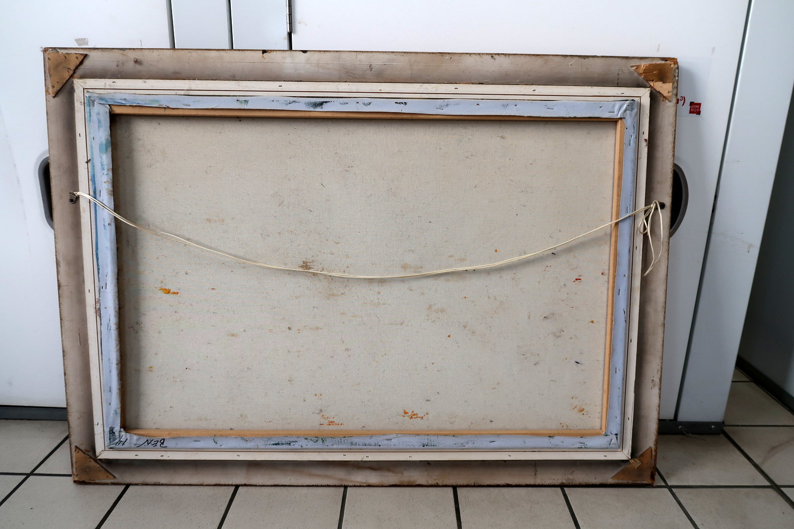 Close-up of the ornate gilded frame corner showing visible cracks and wear consistent with age, surrounding a vintage oil painting of a mother and child.

