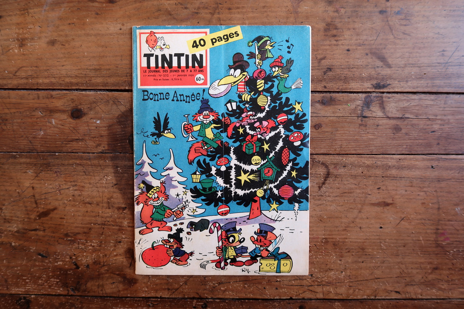 Close-up of the cover art on a 1959 French Tintin comic book magazine showing a colorful holiday scene with characters celebrating around a Christmas tree, with the iconic Tintin header and “Bonne Année!” greeting.

