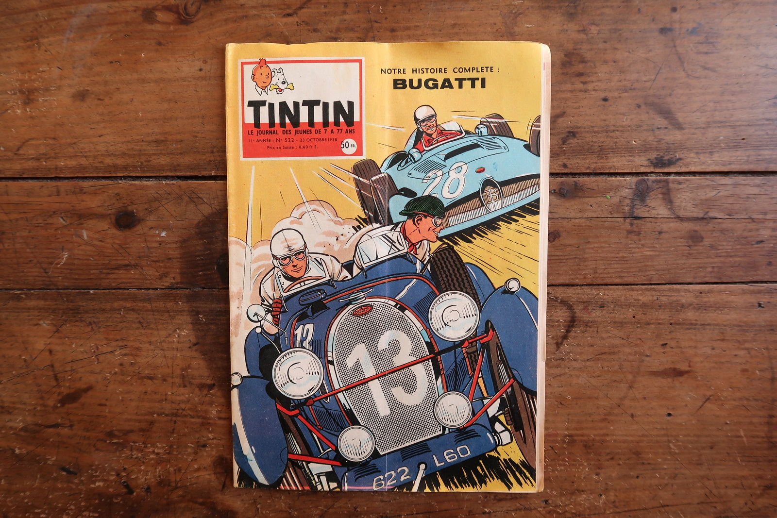 Vintage October 23, 1958 Tintin magazine issue N°522 displayed flat, measuring approximately 8.3 x 11.8 inches, with French language text and bande dessinée artwork, showing a pronounced spine curl consistent with age.

