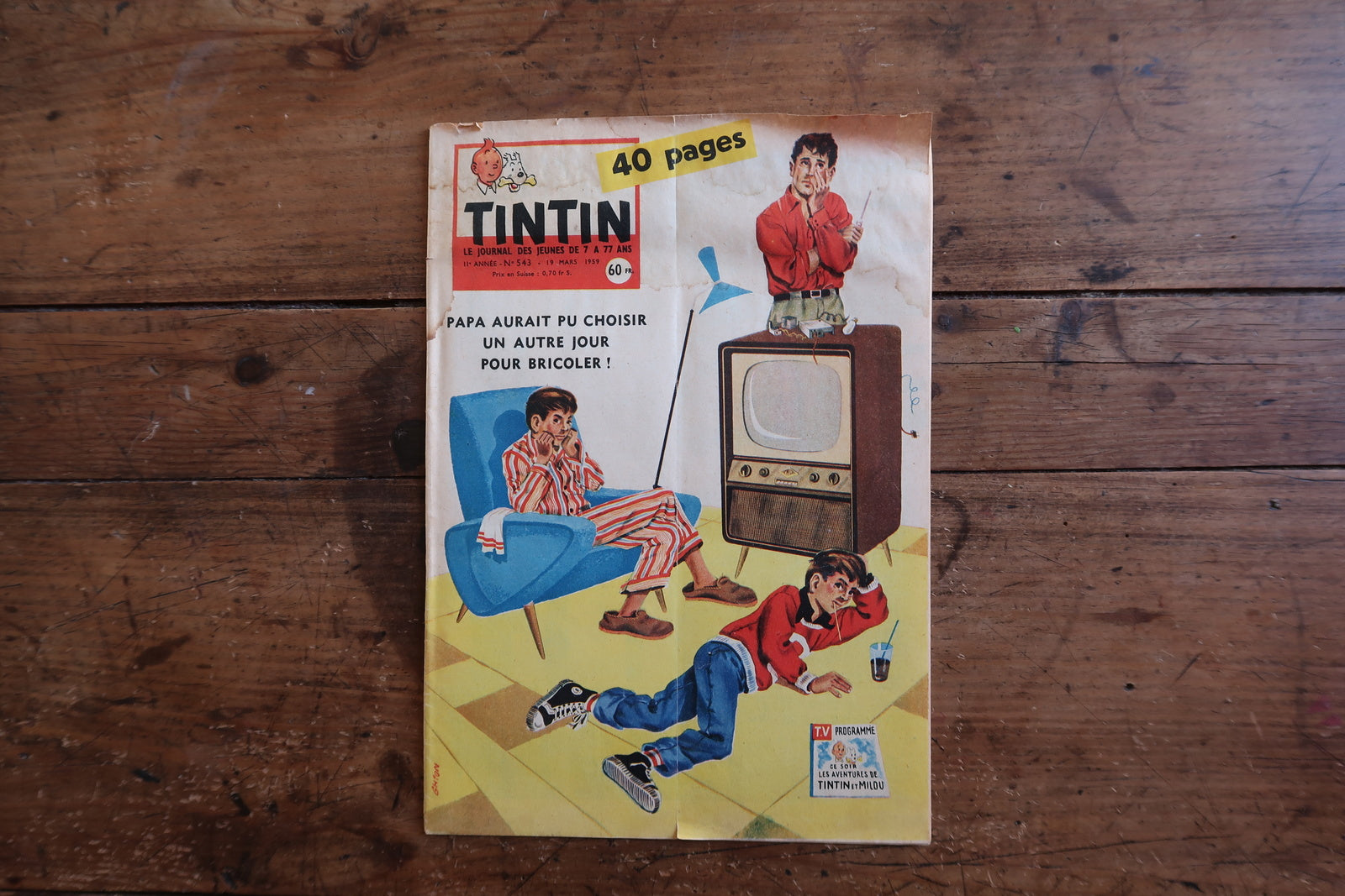 Vintage March 18, 1959 Tintin magazine issue N°542 displayed flat, measuring approximately 8.3 x 11.8 inches, with French language text and bande dessinée artwork, showing cover detached from spine and significant creasing (condition disclosed).

