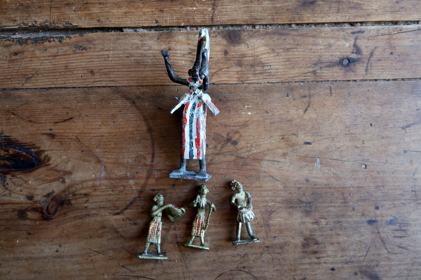 Vintage Quiralu/Starlux/Clairet attributed lead figurine set circa 1950s, featuring a ritual specialist (shaman or ceremonial dancer) in bold vertical striped robe surrounded by three musicians and attendants – a historical artifact of French colonial-era toy manufacturing.

