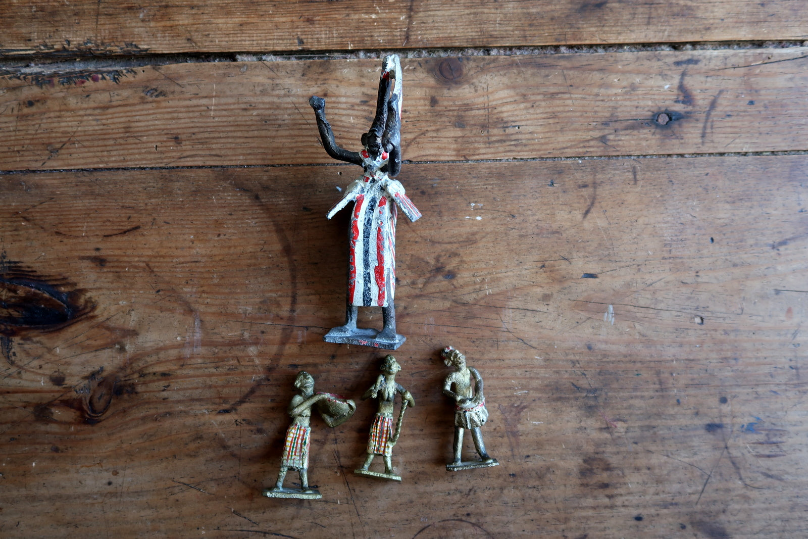 Vintage Quiralu/Starlux/Clairet attributed lead figurine set circa 1950s, featuring a ritual specialist (shaman or ceremonial dancer) in bold vertical striped robe surrounded by three musicians and attendants – a historical artifact of French colonial-era toy manufacturing.


