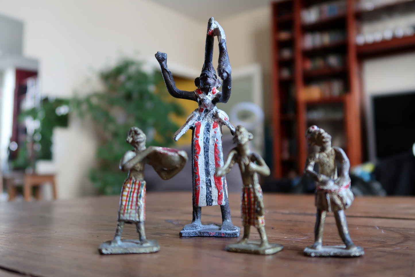Close-up of the staff-bearing attendant figurine from a 1950s French colonial lead toy set, showing a small figure in painted striped loincloth carrying a spear or staff, with original paint showing honest age wear.

