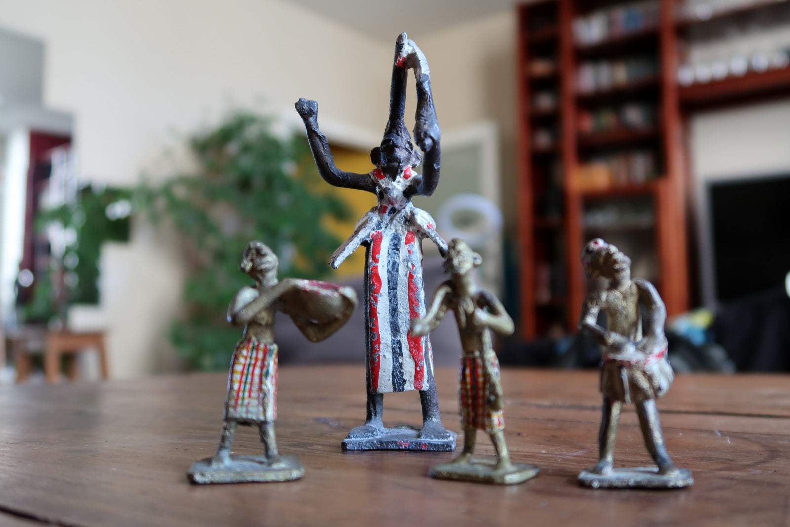 Close-up of the staff-bearing attendant figurine from a 1950s French colonial lead toy set, showing a small figure in painted striped loincloth carrying a spear or staff, with original paint showing honest age wear.

