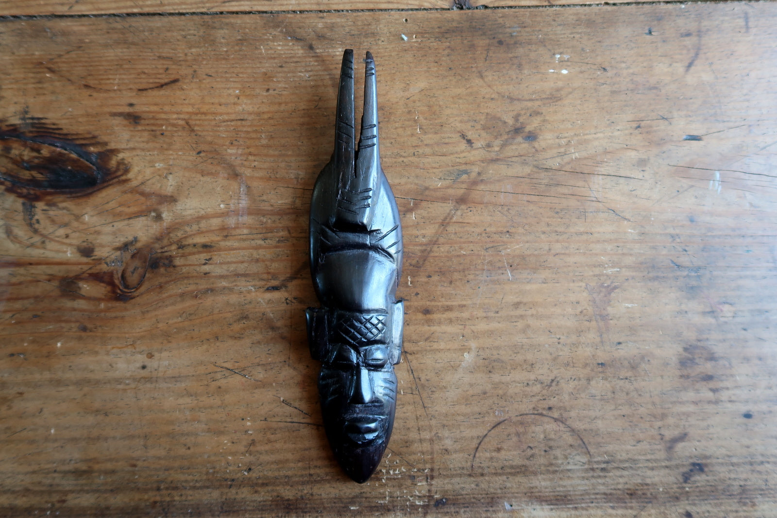 Carved African mask — ebonized wood with bold angular features and twin crest


