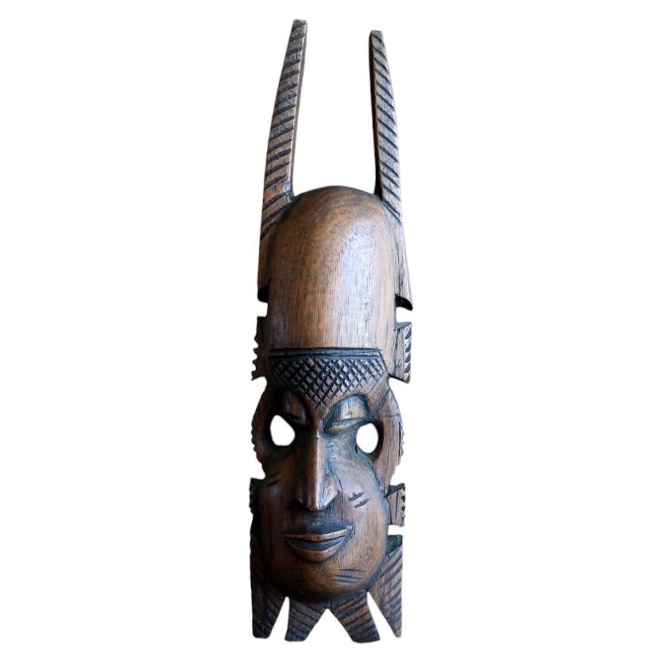 African hardwood mask — carved mask with crown‑style crest and facial scarification

