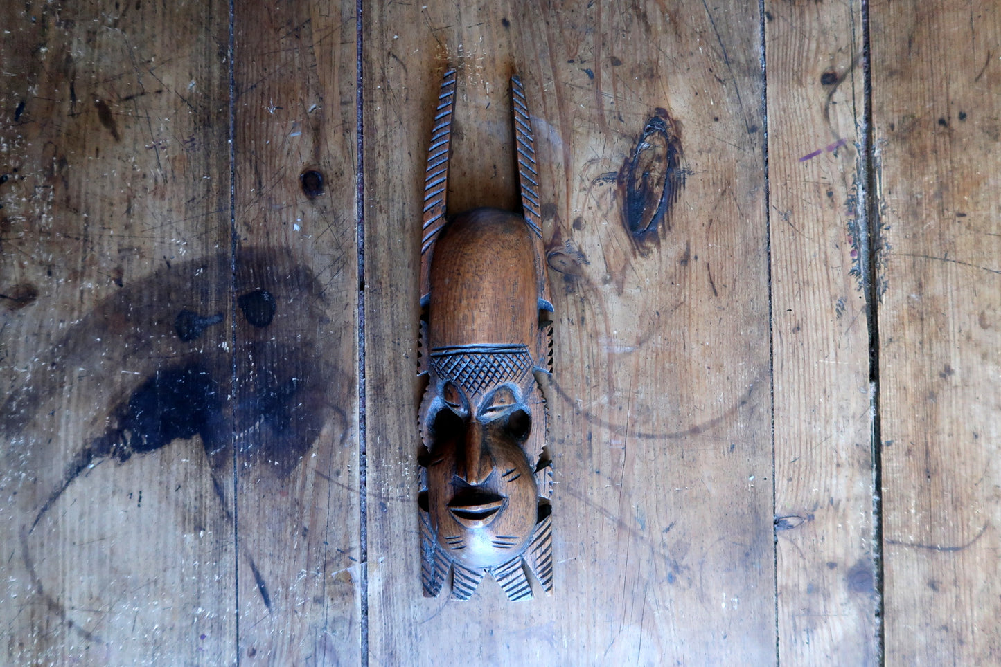 Carved African mask — expressive face with traditional scarification marks

