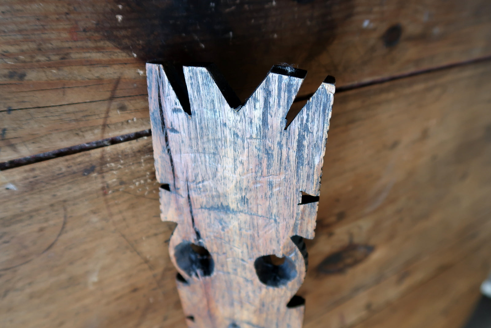 West African hardwood mask — elongated facial features and carved scarification


