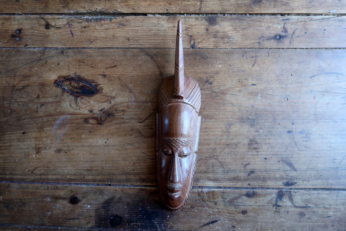 African carved mask — expressive face and single‑horn headdress

