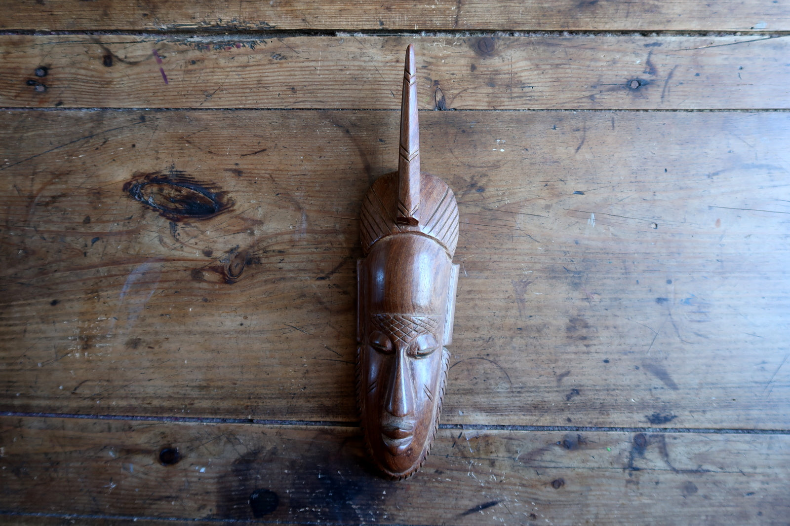 African carved mask — expressive face and single‑horn headdress

