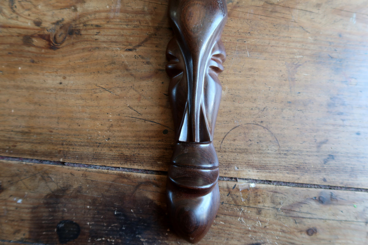 Macro shot of the carved multi-petal leaf crest crowning the mask, showing the natural wood grain running across the spreading fan design.