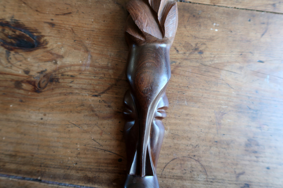 Detail shot of the smooth rounded oval spatula base at the bottom of the elongated African carved wood mask.