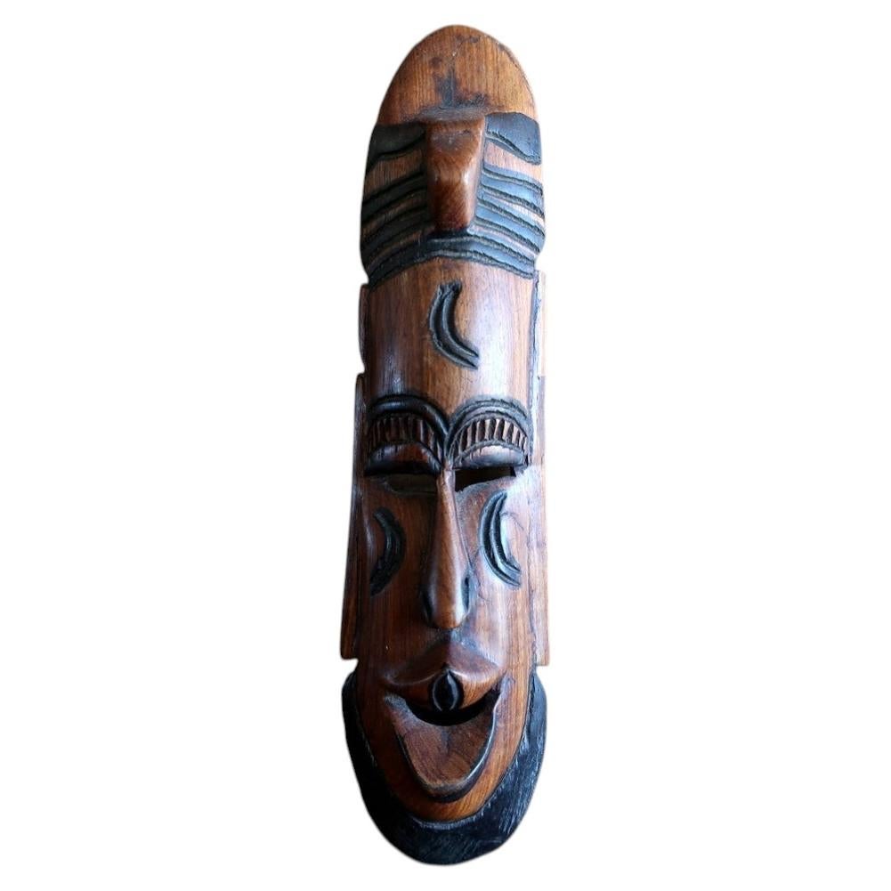 Front view of a West African Baoulé style carved tropical hardwood dance mask with semi-circular forehead scarification and an elongated facial composition.
