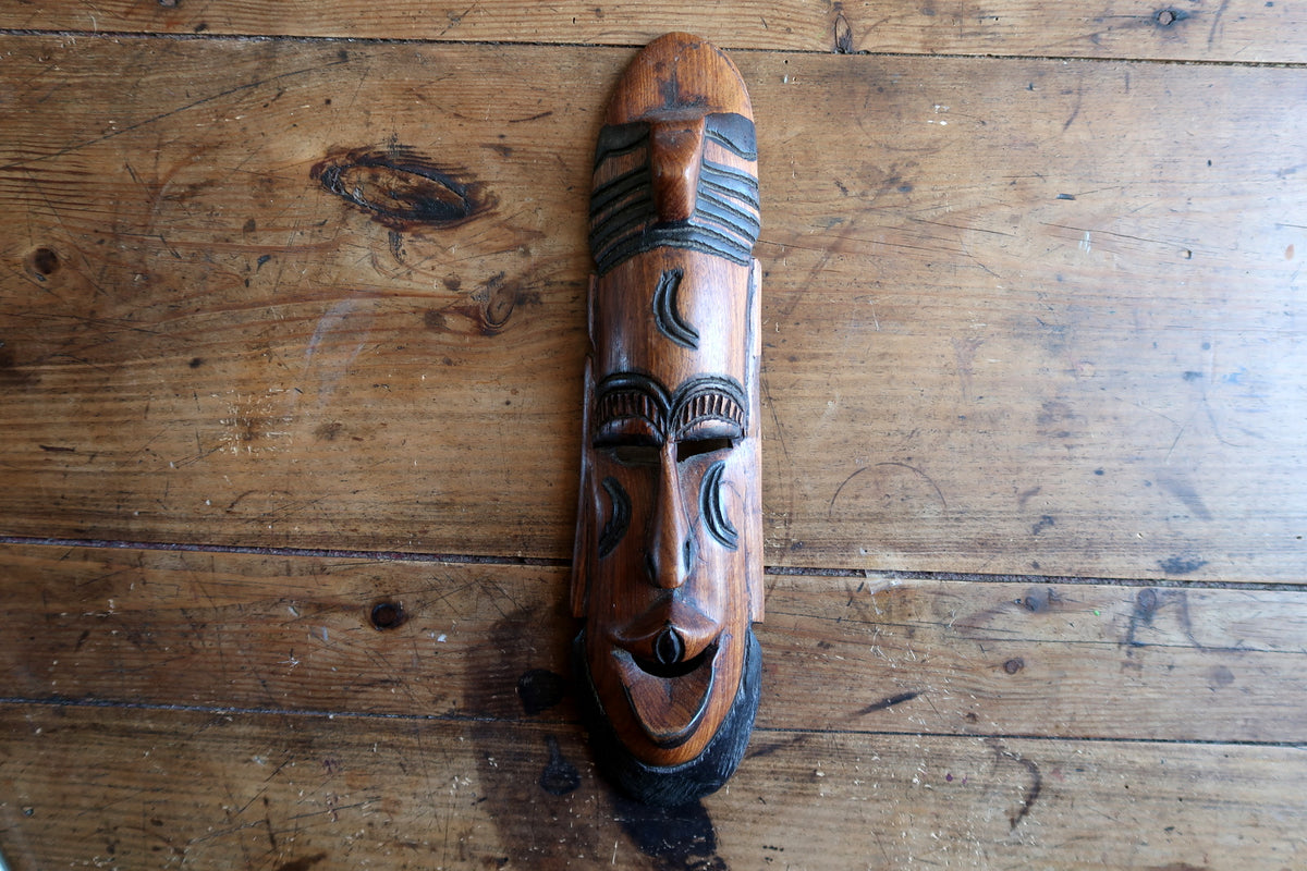 Detail shot of the carved forehead showing the semi-circular arch scarification band with parallel lines following the curve of the brow.