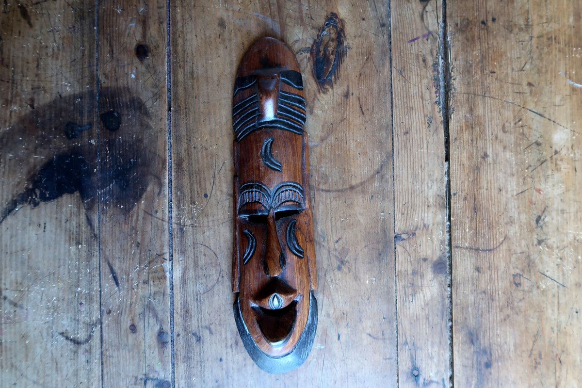 Profile view demonstrating the slim depth, prominent nose bridge, and architectural facial contours of a carved wooden Baoulé style mask.
