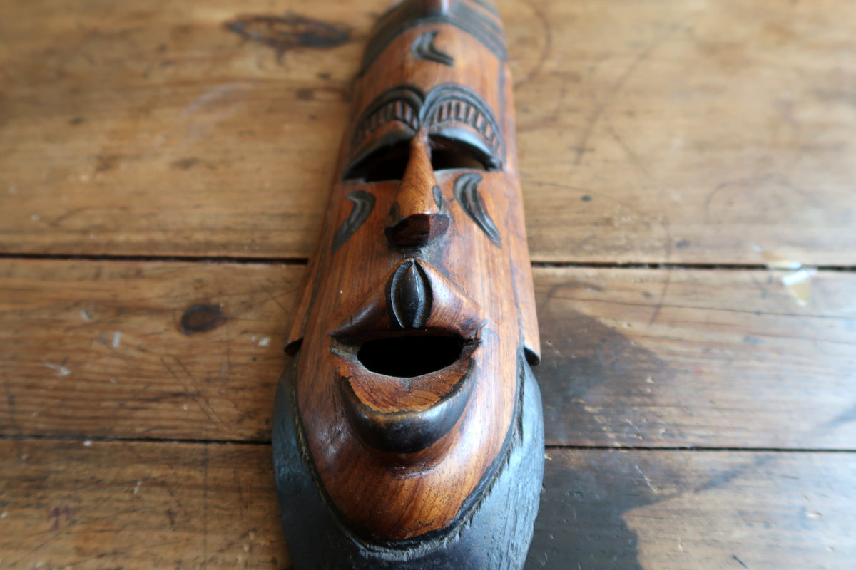 Overhead view focusing on the curved upper crest and smooth top rim of the hand-carved wooden dance mask.