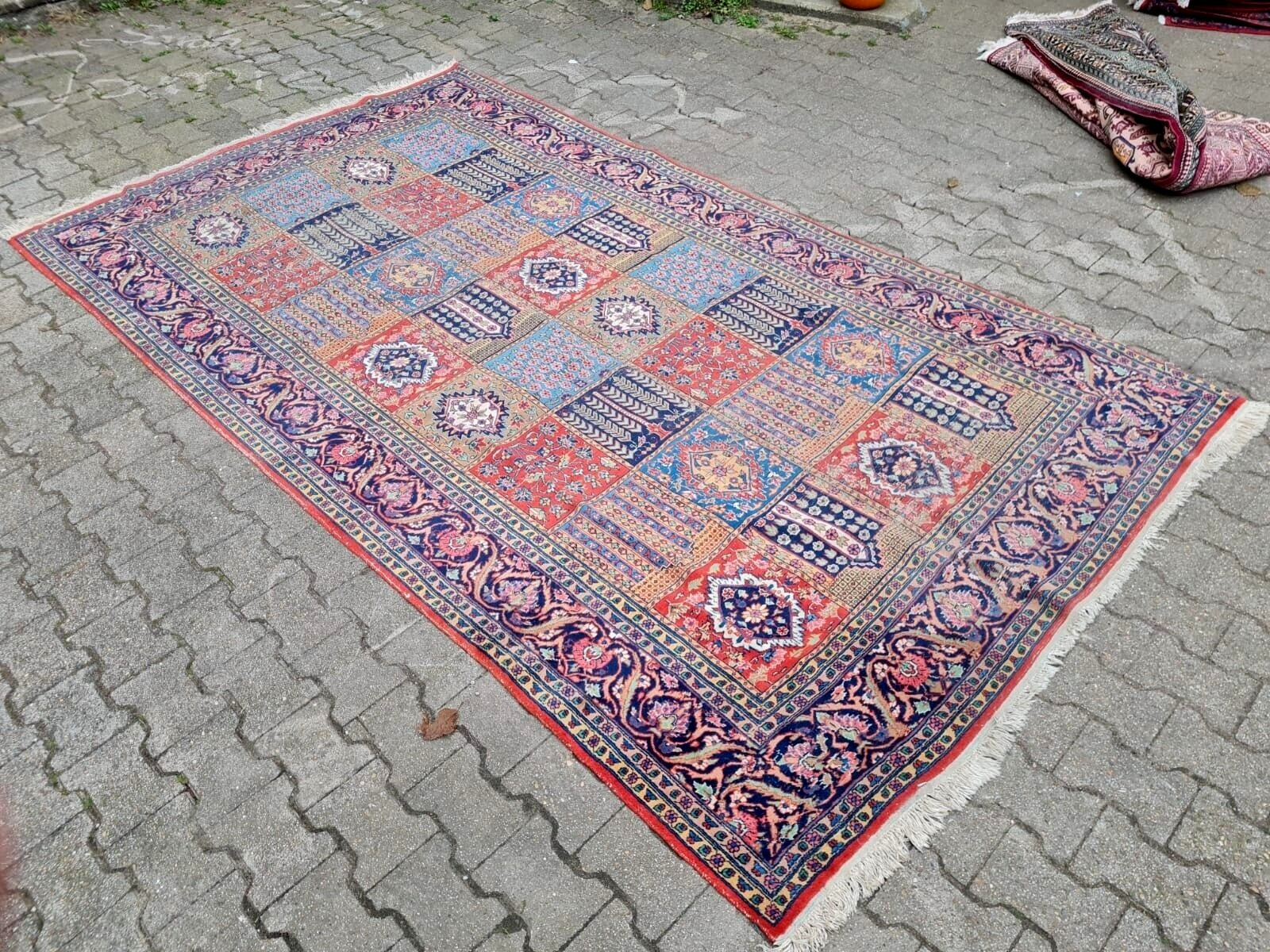 Persian rug showing localized low pile areas consistent with age.
