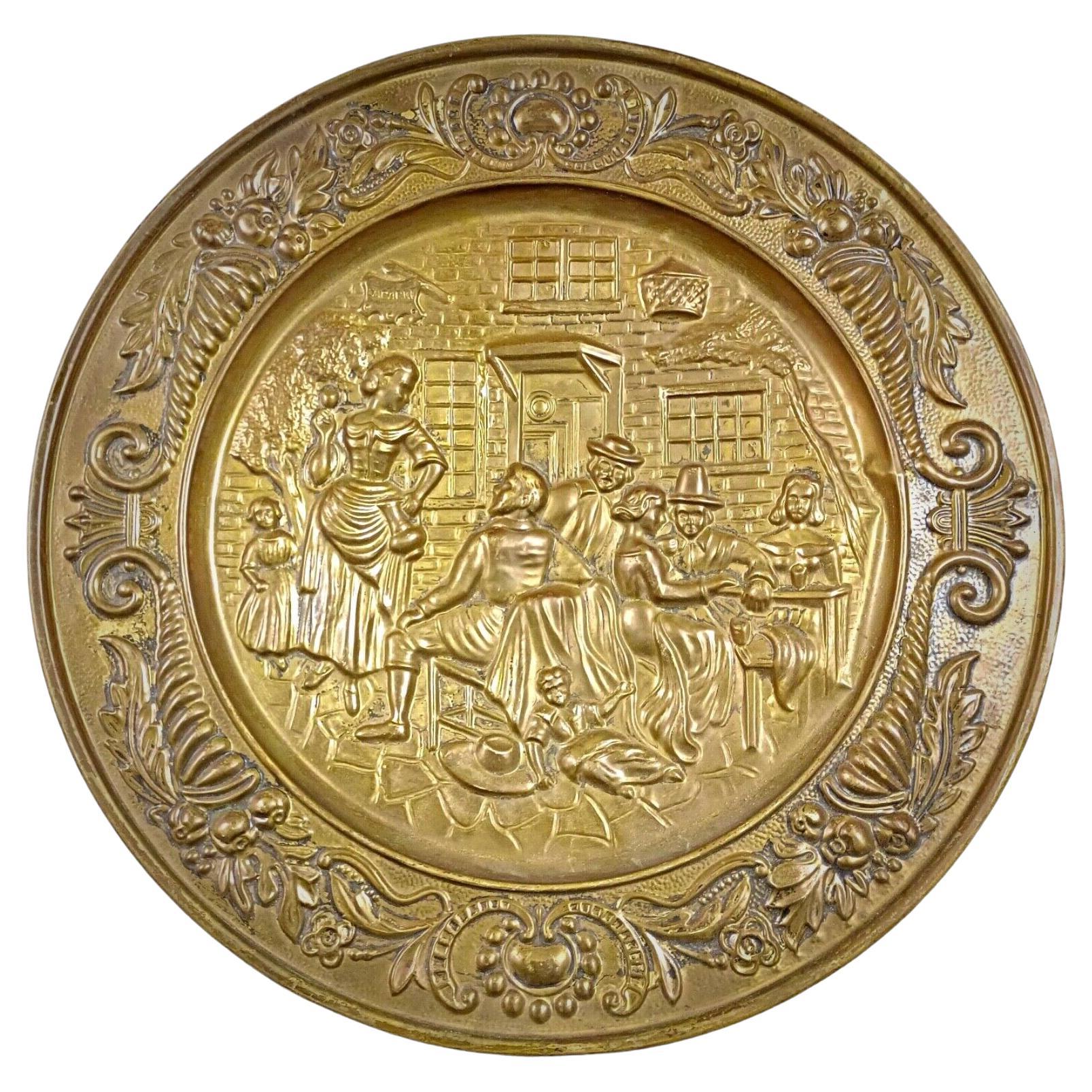Antique 20th-century brass plate with a repoussé tavern scene

