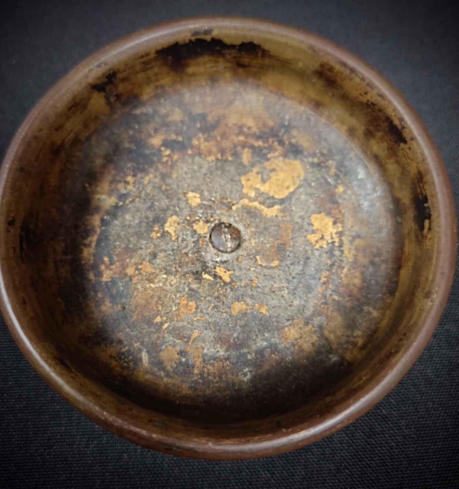 Detailed shot of surface scratches and oxidation on brass dish.
