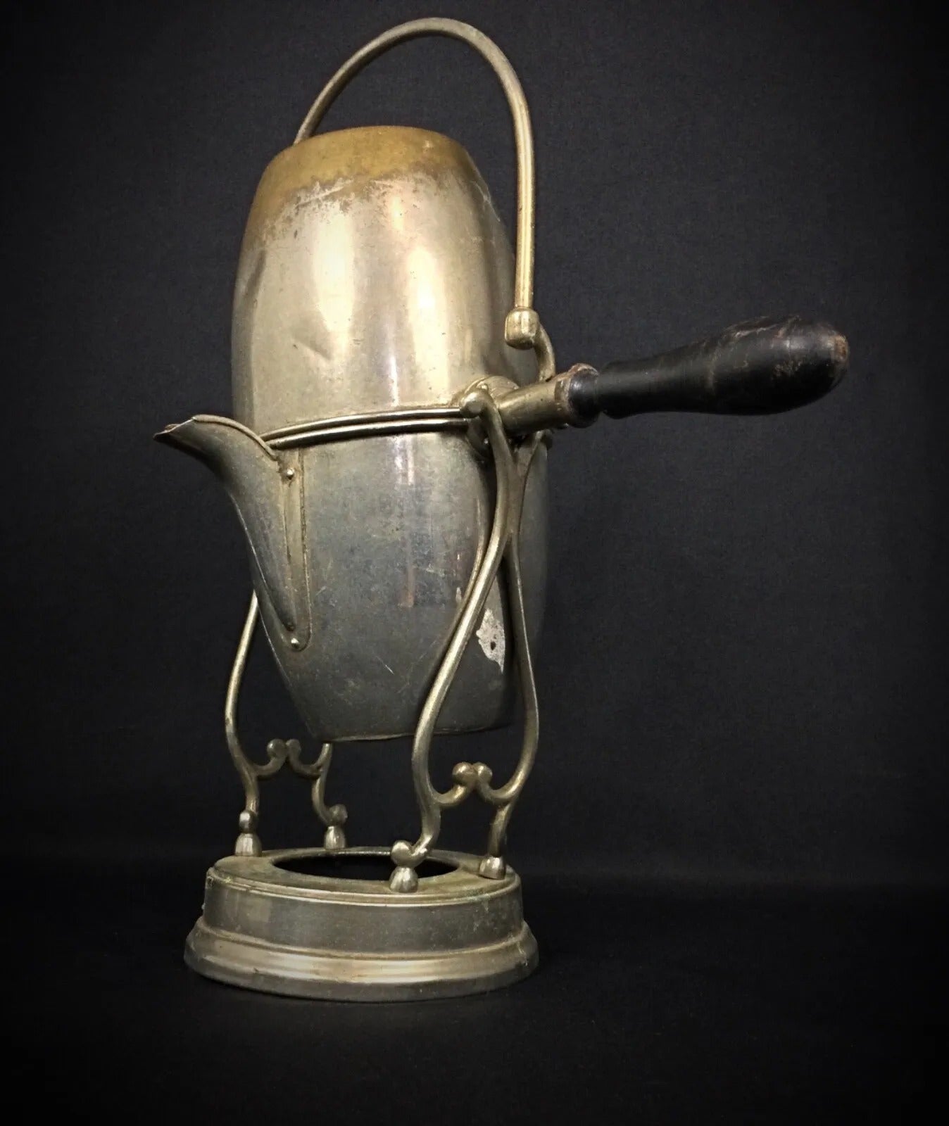 Full view of a French or European tilt coffee pot resting on its original tilting base with decorative metalwork