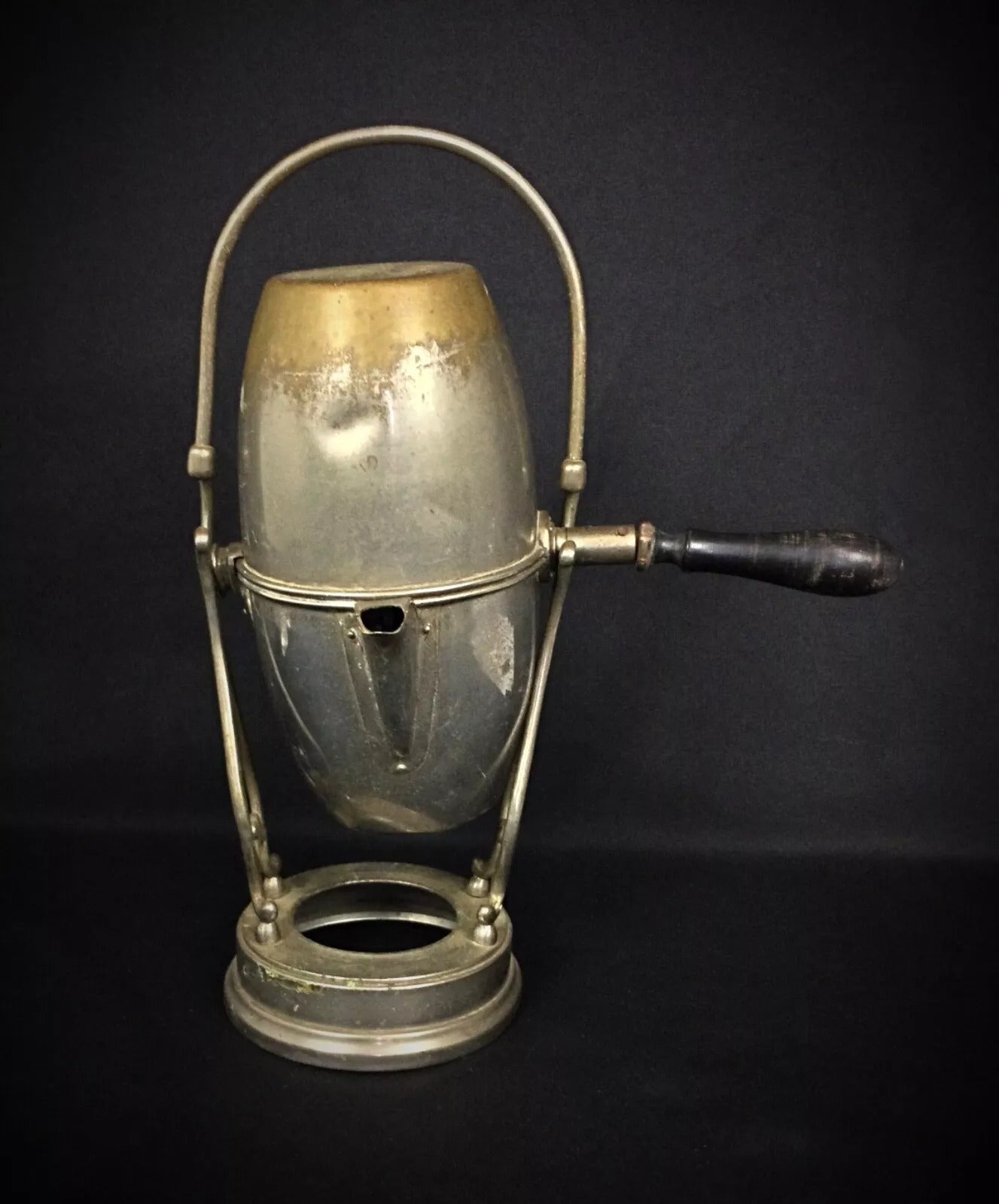 Side view showing the graceful silhouette and functional tilt mechanism of an antique pierced metal coffee server