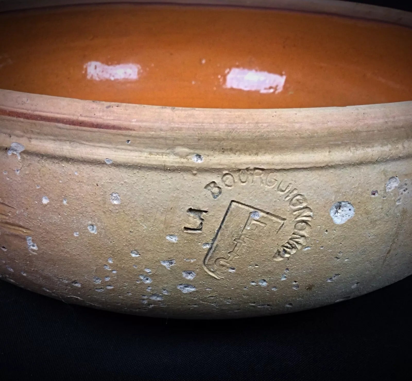 Full view of a rustic French pottery pan showing warm terracotta tones and traditional craftsmanship